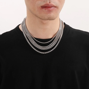 Detail of silver layered box chain necklace worn by a male model for styling effect