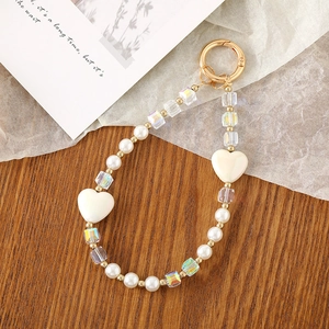 Detailed macro view of white pearl and crystal heart beaded keychain on wooden desk