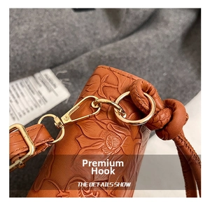 Détail du motif lotus embossé sur sac en cuir marron avec crochet doré