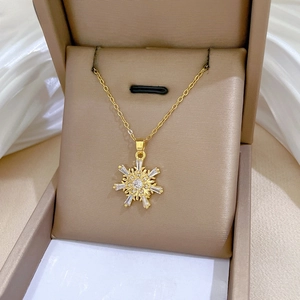Detailed shot of gold snowflake pendant with zircon crystals in a brown velvet jewelry box