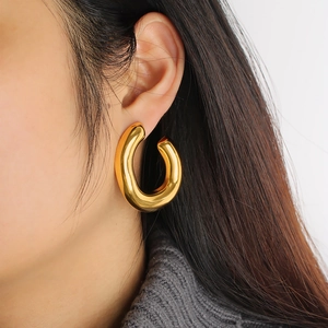 Close-up of a model wearing a thick polished 18k gold-plated C-shaped hoop earring