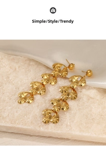 Close-up of golden long drop earrings with matte texture and starburst pattern detail