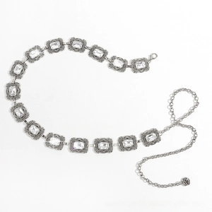 Détail de la ceinture chaîne argentée vintage avec cristaux carrés et pendentif rose