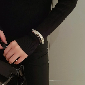 Sleek silver round bangle styled over a black sleeve for a modern minimalist look