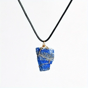 Detail of wire-wrapped raw lapis lazuli pendant on a black cord necklace