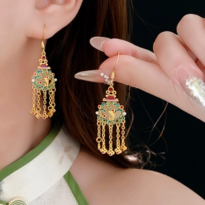 Détail de boucles d'oreilles pompons plaquées or 18 carats avec émail et motif poisson