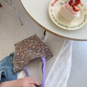 Detail of purple floral corduroy tote bag showing metal snap button and fabric texture