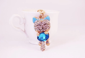 Close-up of golden lucky cat keychain with light blue stone and sparkling crystal inlay