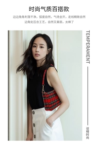 Close-up of red and black checkered baguette bag with gold hardware worn as a shoulder bag