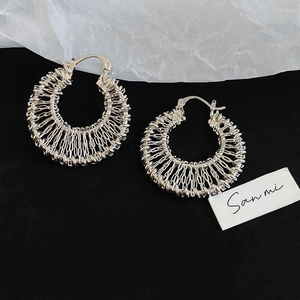 Close-up of silver hollow woven hoop earrings with intricate braided texture design