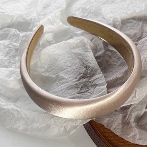 Macro shot of luxury champagne satin padded headband with smooth silky texture