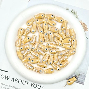 Detail of yellow fish-shaped ceramic beads for DIY jewelry making with threaded hole