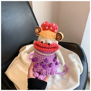 Detail of handmade purple crochet bag with sausage mouth character and pearl accents