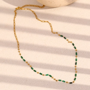 18K gold plated stainless steel necklace with green natural stones on beige surface