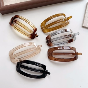 Close-up of minimalist oval cutout hair clips in various tortoiseshell and solid resin colors