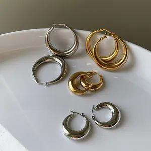 Detail von klobigen Gold- und Silber-Creolen in verschiedenen Größen auf weißem Teller