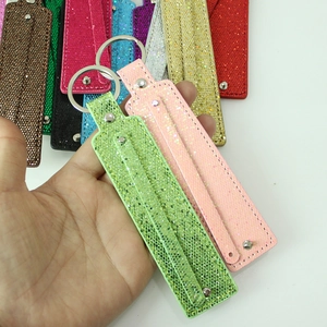Close-up of DIY glitter keychain charms in green and pink with metal rings