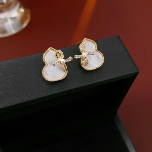 Macro view of gold-plated gourd stud earrings with white inlay and crystal bow detail