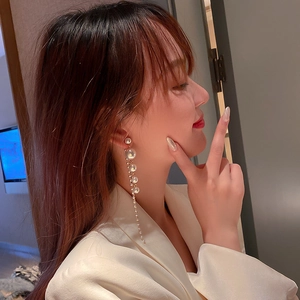 Elegant gold drop earrings with pearls and tassels shown on model's side profile