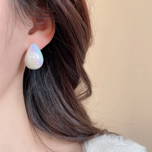 Close-up of teardrop acrylic stud earrings with iridescent pearl finish on model