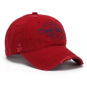 Détail d'une casquette en coton rouge délavé avec broderie bleue et bords usés style vintage