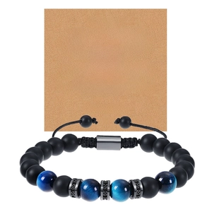 Détail de perles noires mates et bracelet oeil de tigre bleu sur carte de message kraft