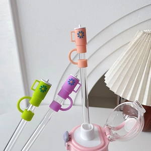 Close-up of colorful flower silicone straw covers on glass straws in a pink water cup