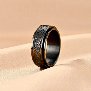Matte black titanium spinner ring with Celtic knot relief on luxury satin background