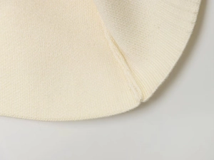 Close-up of fine machine knit texture and stitched edges on cream knit skirt suit