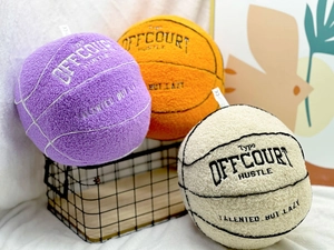 Plush basketball pillows in purple, orange, and beige displayed in a wire basket decor