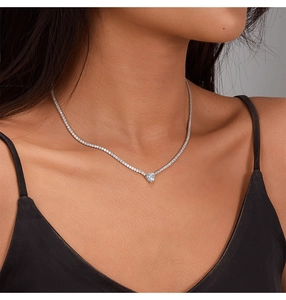 Close-up of a silver 925 heart pendant tennis necklace worn by a female model