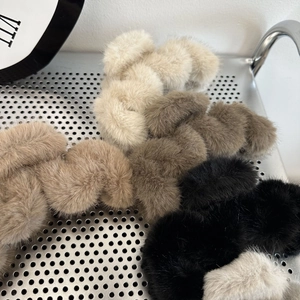 Close-up of five fluffy faux fur scrunchies in cream and brown tones on a metal tray