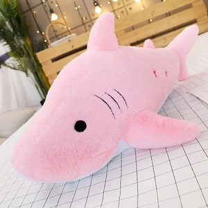 Pink shark plush toy skin shell on a white checkered bed in a cozy bedroom