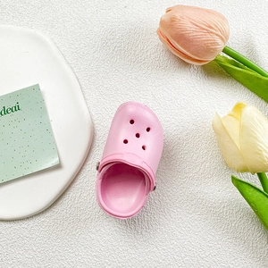 Close-up of pink slipper phone stand with cute tulip decor on a clean white surface