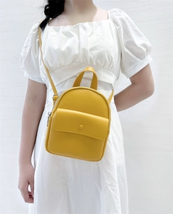 Detailed view of yellow lychee grain faux leather mini backpack on a model
