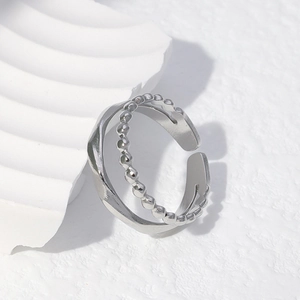 Minimalist double-layered silver ring with bead texture and wave design on a white background