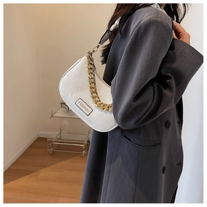 Detail of white half-moon shoulder bag with gold chain and striped fabric strap