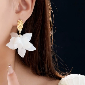Close-up of elegant creamy white flower petal earrings with textured gold metal studs