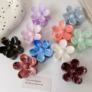 Vue à plat de pinces à cheveux fleurs colorées avec texture marbrée sur fond esthétique