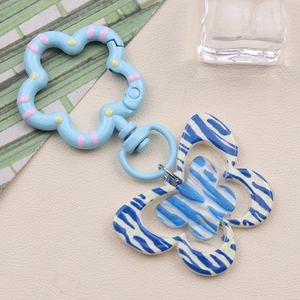 Detail of blue zebra pattern butterfly keychain with a floral clasp on a textured background