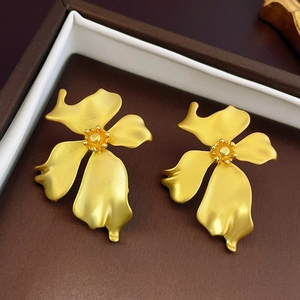 Macro shot of gold floral earrings with matte finish petals in a brown luxury jewelry box