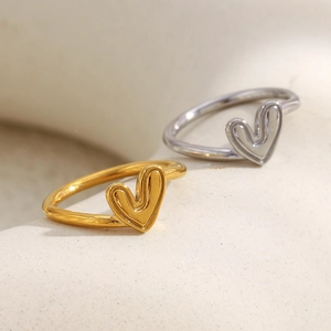 Bagues cœur minimalistes plaquées or 18 carats et argent sur fond de pierre texturée