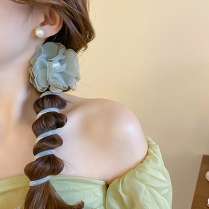 Close-up detail of green fabric flower hair accessory and wire hair tie, elegant daily look.