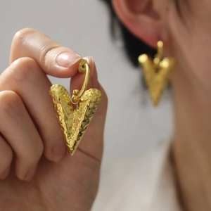 18K gold plated heart earrings with textured hammered finish on model