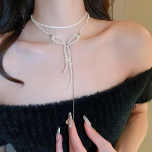 Elegant double-layered pearl bow necklace with fringe tassels on a black knit sweater