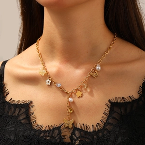 Collana dorata con farfalla traforata, ciondoli a fiore di perla e accenti di catena nappa