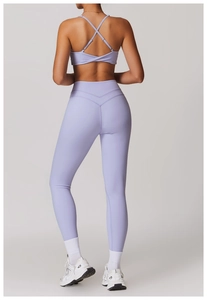 Dettaglio dei leggings a vita alta con cucitura a V e reggiseno sportivo incrociato lilla