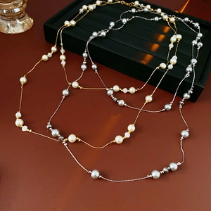 Detailed view of layered faux pearl beaded necklaces with gold and silver chain accents
