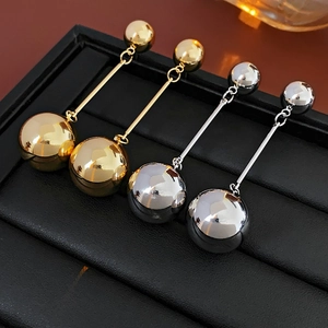 Close-up of gold and silver metal ball drop earrings with a polished mirror finish