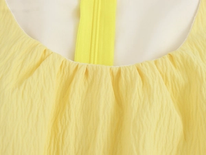 Dettaglio del collo rotondo giallo con pieghe arricciate e zip invisibile